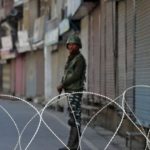 An Indian security force personnel stands guard in front of the closed shops during restrictions following scrapping of the special constitutional status for Kashmir by the Indian government, in Srinagar.