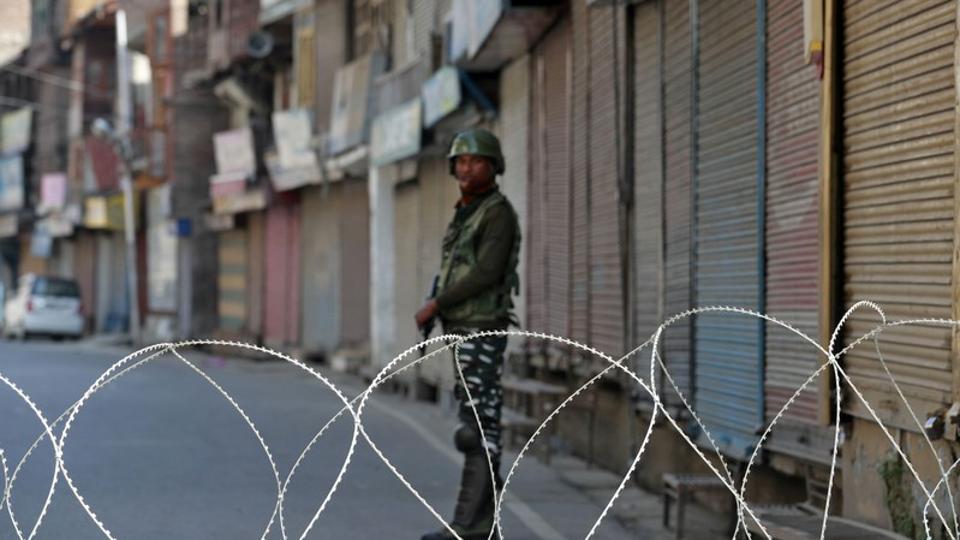 An Indian security force personnel stands guard in front of the closed shops during restrictions following scrapping of the special constitutional status for Kashmir by the Indian government, in Srinagar.