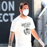 In this photo provided by FC Barcelona, Lionel Messi walks wearing a protective face mask at the club's training ground.