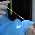 Health worker carefully drops swab in VTM after collecting sample from public.