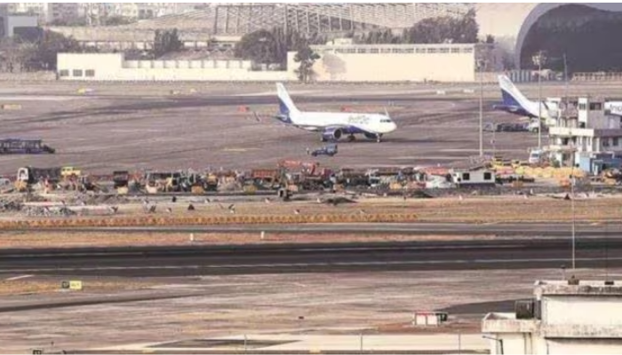 Aircraft at Mumbai Airport with maintenance crews working on the runway before monsoon season.